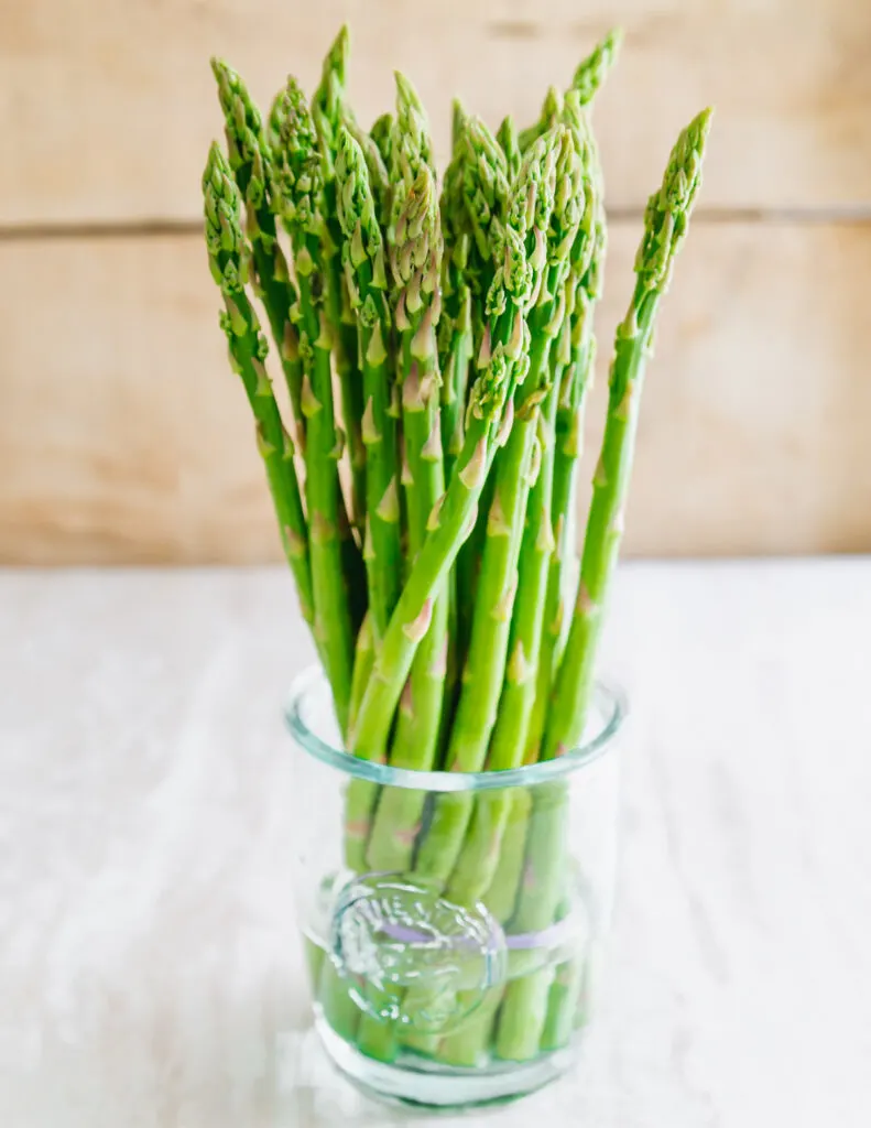 raw asparagus in a glass with water