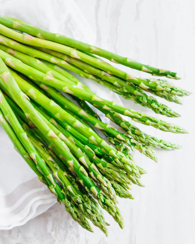 raw asparagus laid out on a kitchen cloth.