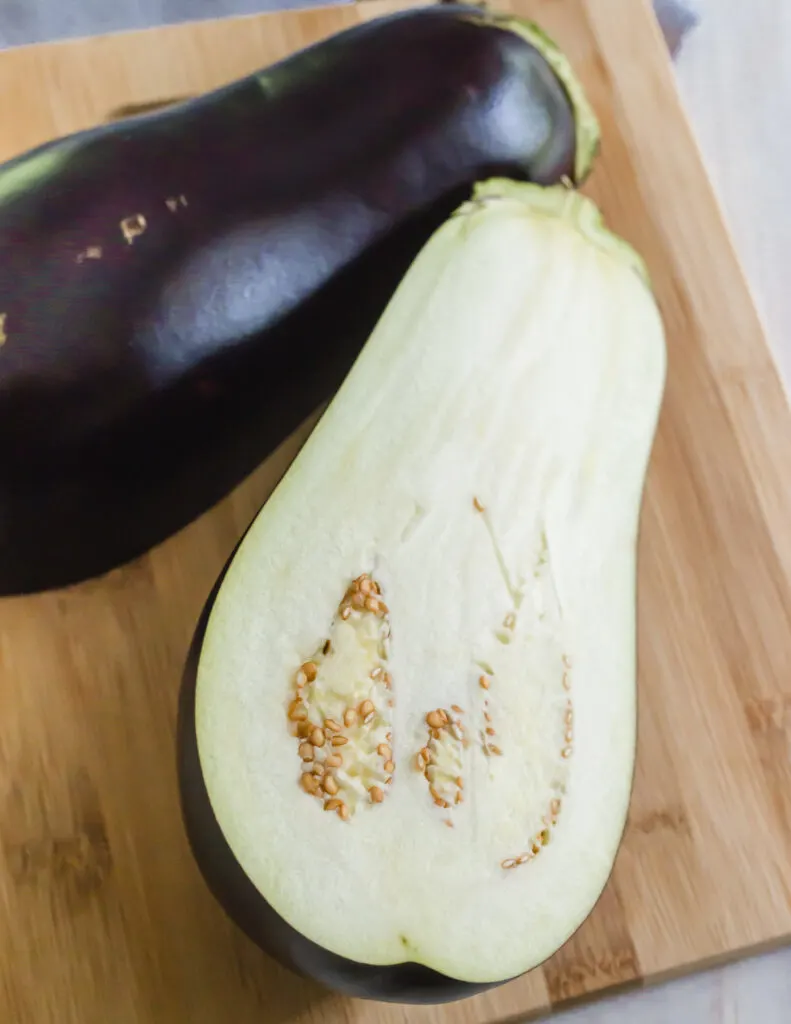 Can dogs eat eggplant? - eggplant sliced in half on a cutting board.