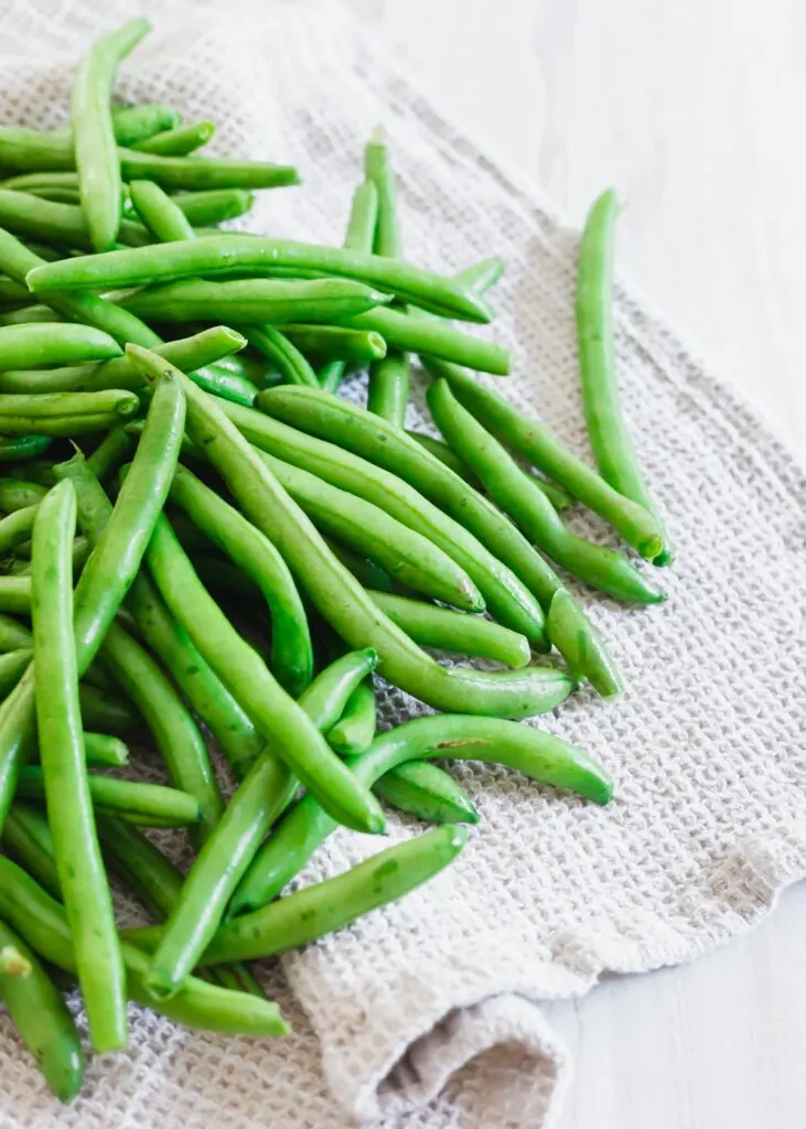 Raw washed organic green beans on a kitchen towel.