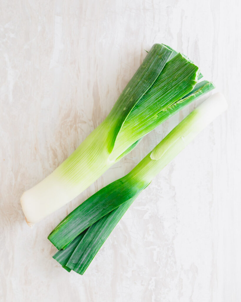 Two raw leeks on a table.
