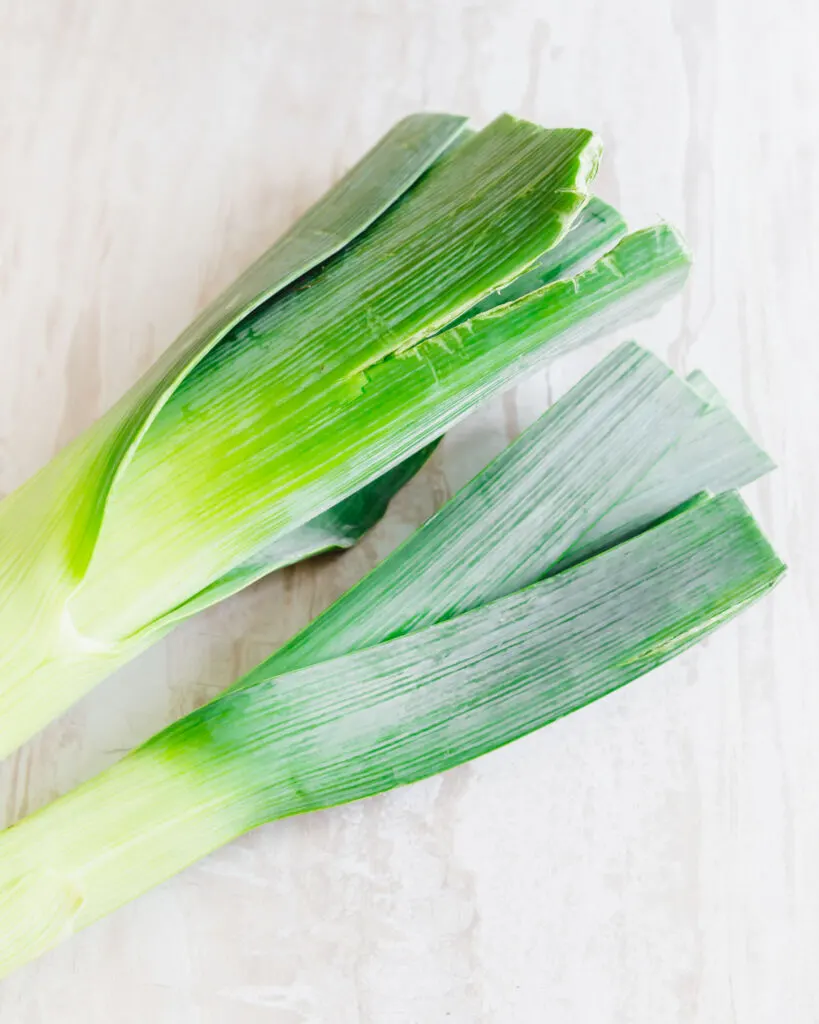 Close up of two intact raw leeks.