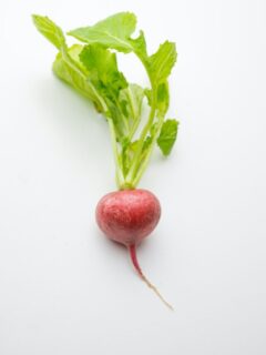 A radish with green leaves on a white background.
