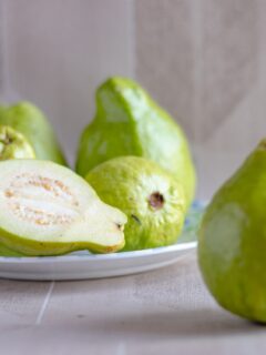 Guava on a plate with one sliced in half.