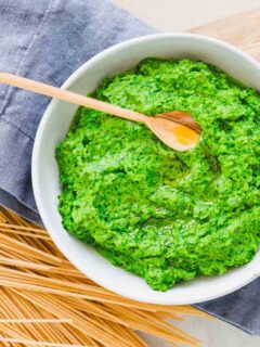 A bowl of green pesto with a wooden spoon.