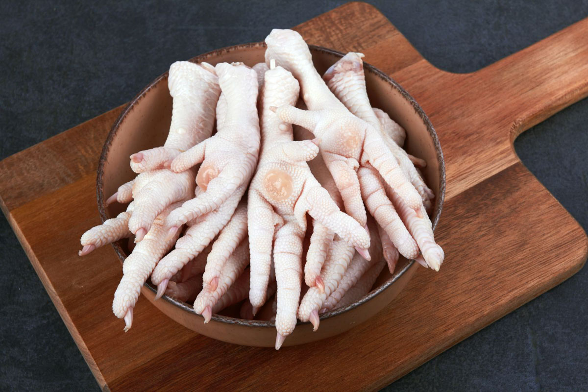 Chicken feet in a bowl on a wooden table.