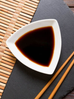 A bowl of asian sauce and chopsticks on a table.